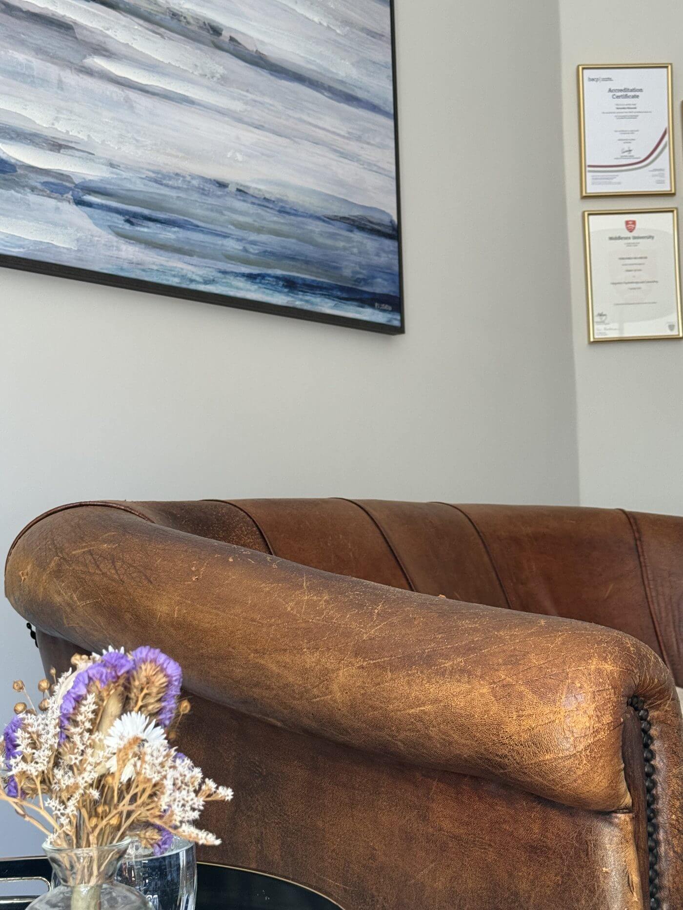 Consulting room with leather chesterfield sofa, vintage rug, and bookshelves
